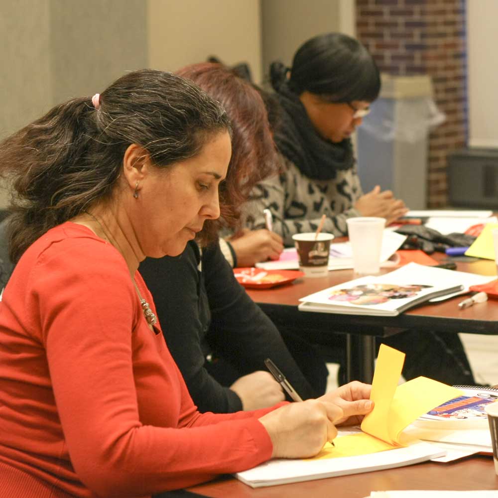 Women writing on pad of paper in workshop